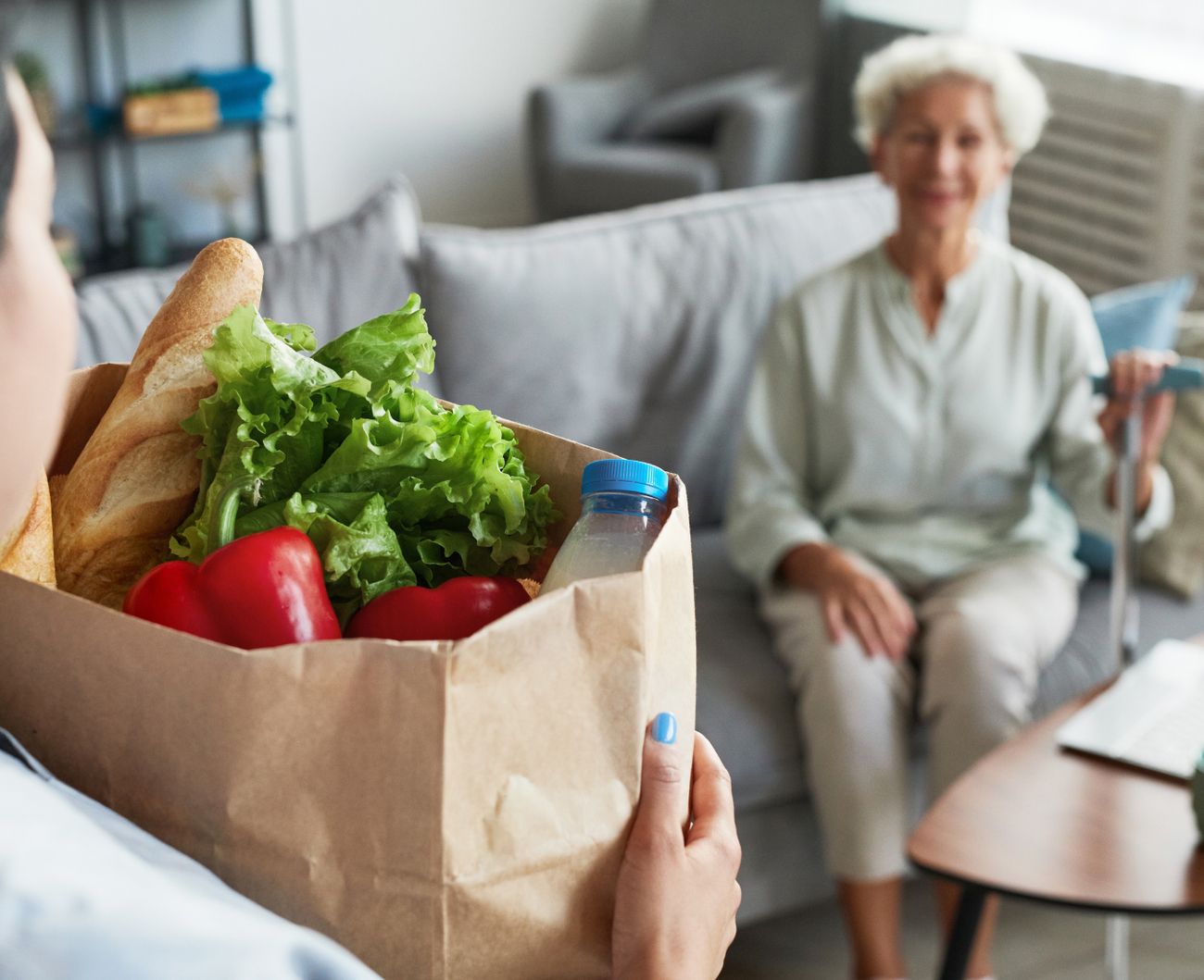 Eine Frau steht mit einer Papiertüte voller Einkäufe und zeigt ein zufriedenes Lächeln.